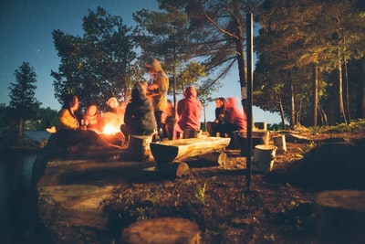 夜间，一群人在篝火旁靠近树木